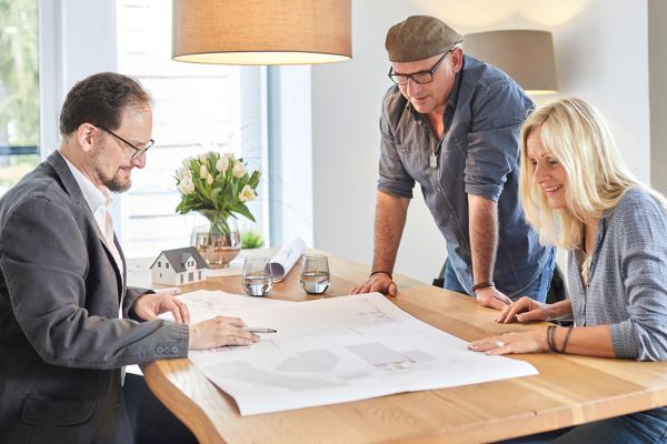 Architekt mit Kunden am Tisch mit Bauplan